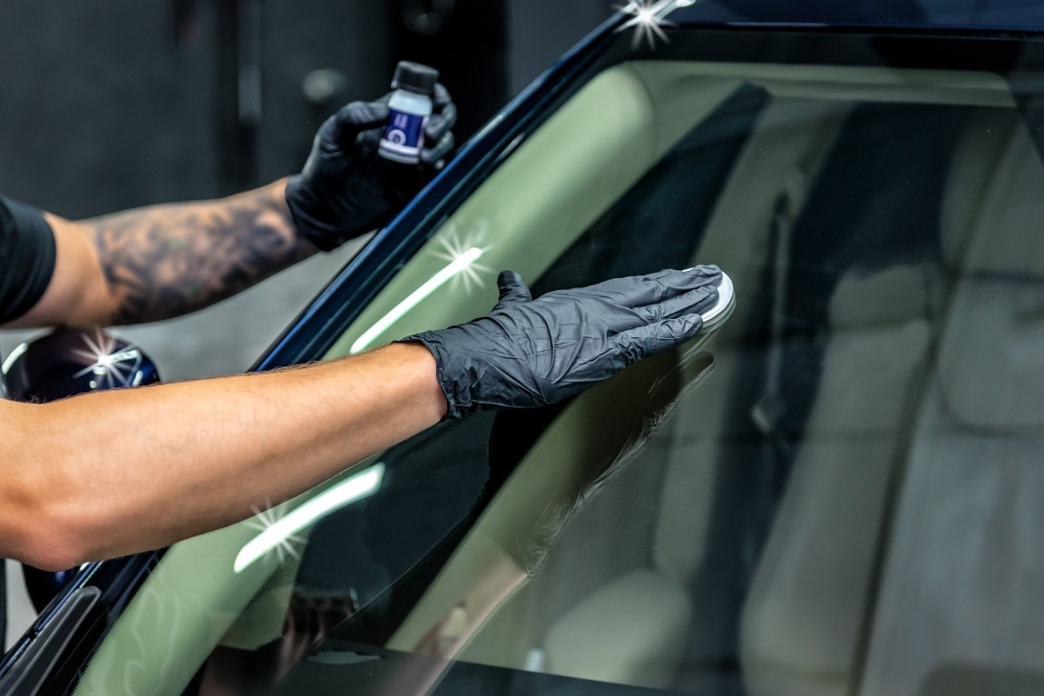 A picture of a person polishing the glass of a car