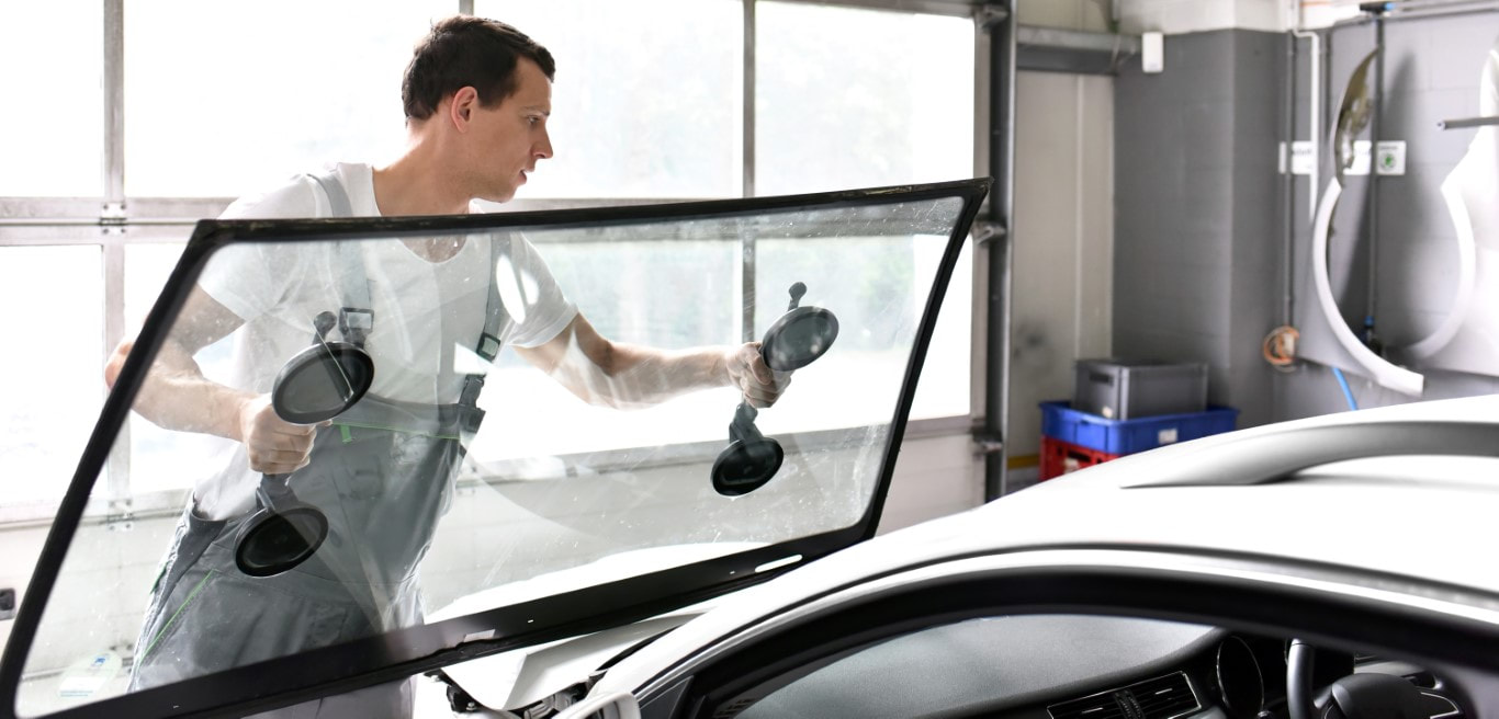A picture of man replacing the windshield of a car